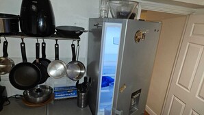 A kitchen with a refrigerator, pots, pans, and a box of foodservice foil.