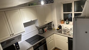A compact kitchen with white cabinets, a built-in oven, a microwave, a sink, and a dishwasher.
