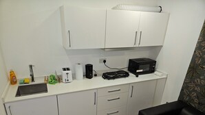 A compact kitchenette with a sink, a toaster, a kettle, and a microwave. There is a small table and a chair in the room. - 1 Bed Flat - Sleeps 2 - Parking - Garden (London)