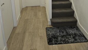A staircase with a dark carpeted handrail and a black marble mat at the bottom. - 1 Bed Flat - Sleeps 2 - Pets - Garden - Parking (London)
