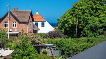 A coastal residential area with houses, a clear sky, and a view of the sea.