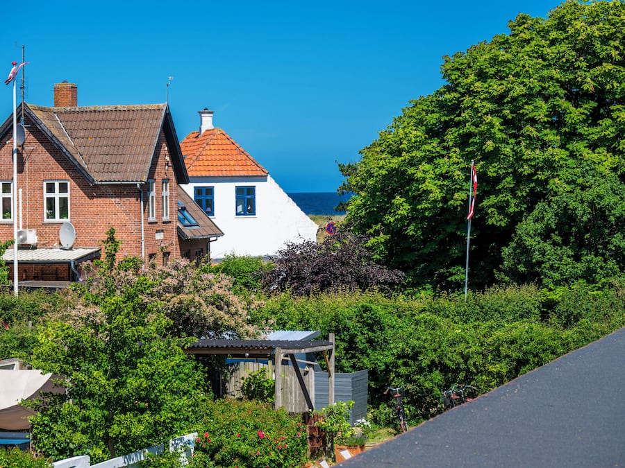 A coastal residential area with houses, a clear sky, and a view of the sea.