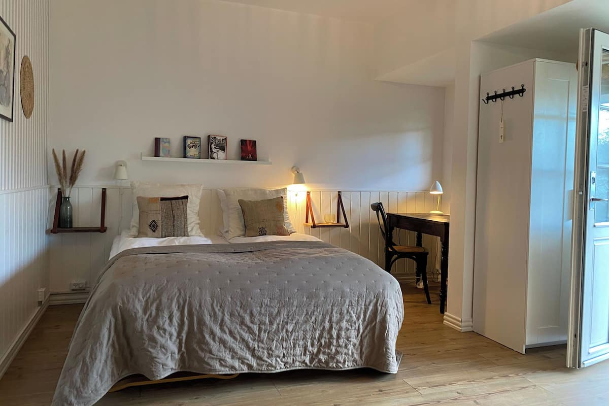 Quarto com cama, mesas de cabeceira, escrivaninha e guarda-roupa.