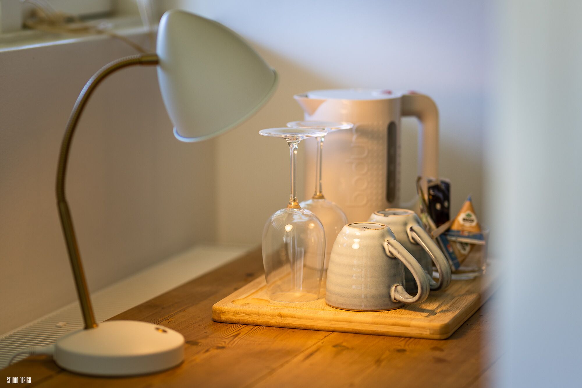 Una mesa de madera con una lámpara, un vaso, una jarrón de cerámica y un recipiente.