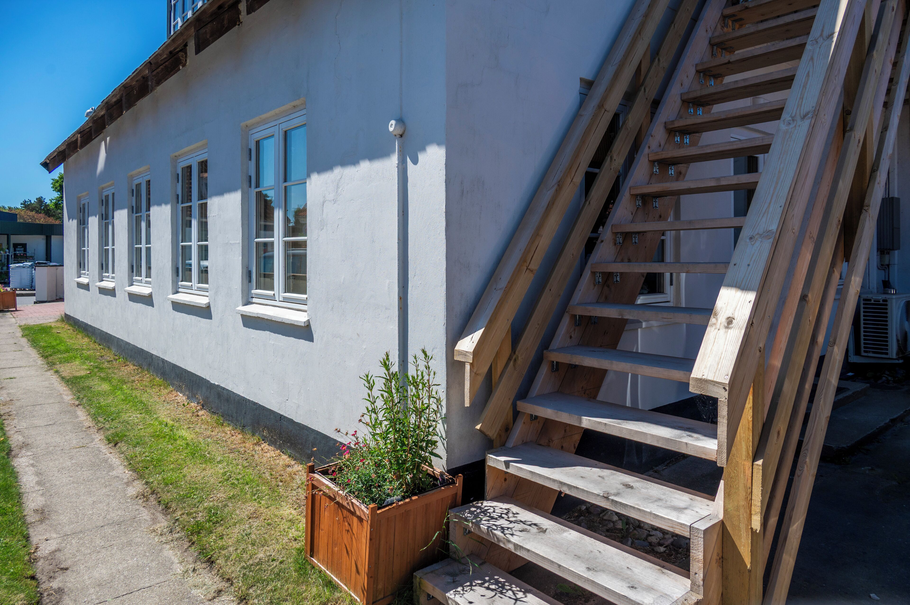 Un bâtiment doté de nombreuses fenêtres, d’un escalier en bois et d’un jardinier avec des plantes.