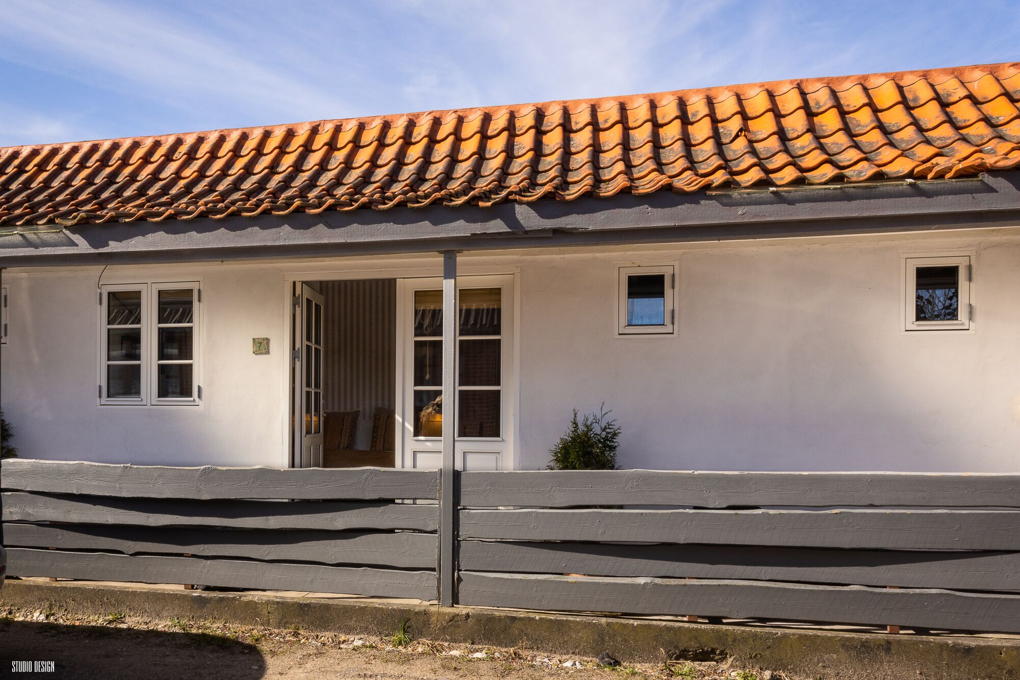 A white building with a tiled roof, a wooden fence, and a small window.