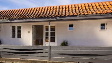 A white building with a tiled roof, a wooden fence, and a small window.