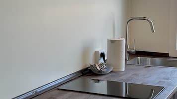 Una cocina moderna con encimera de madera, un lavamanos integrado y una lámpara colgante.