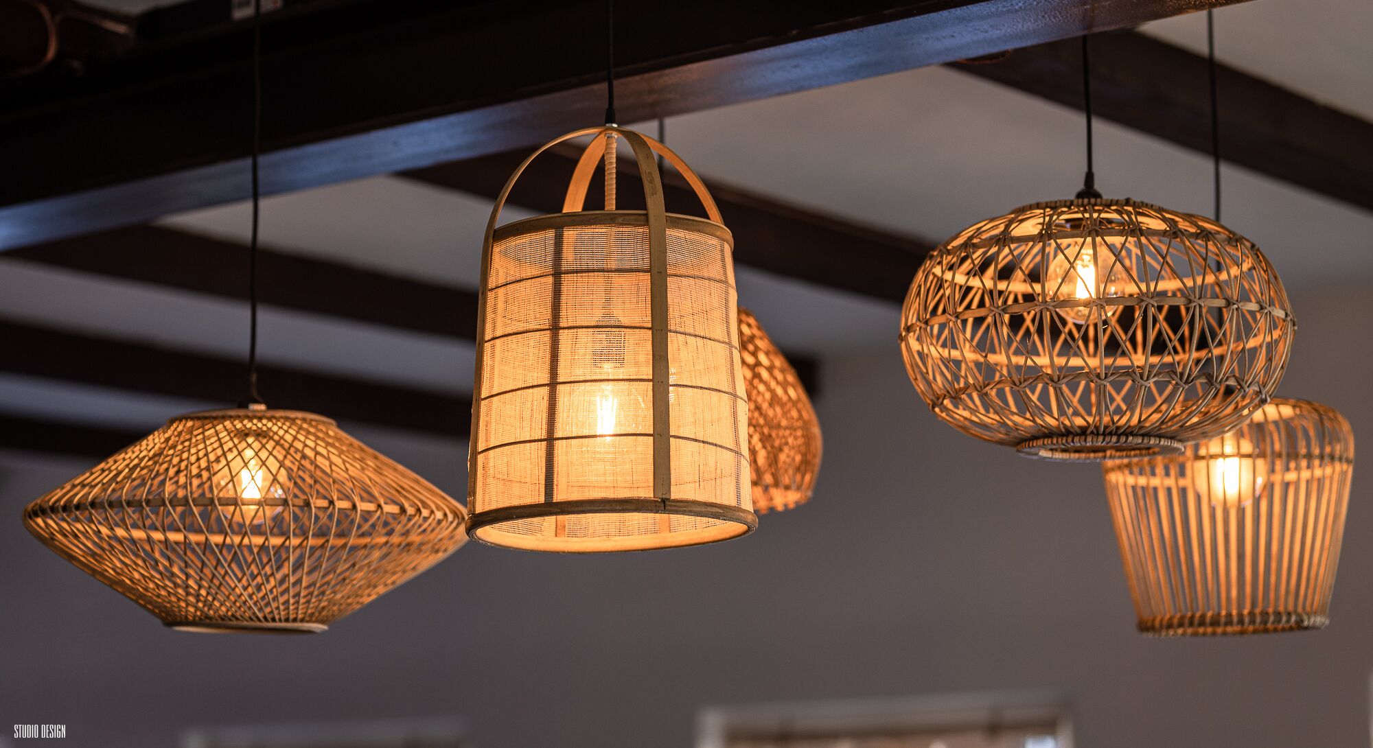 A series of hanging, woven light fixtures in a modern interior setting.
