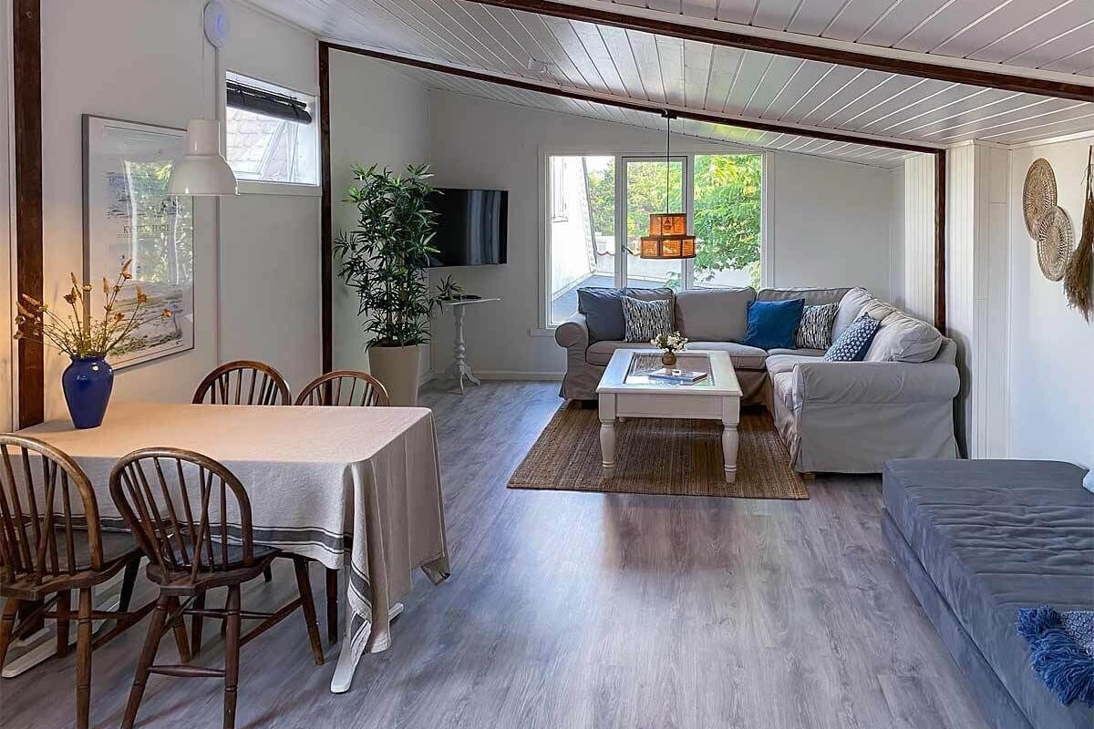 Uma sala ampla com mesa de jantar, cadeiras, sofá e televisão.
