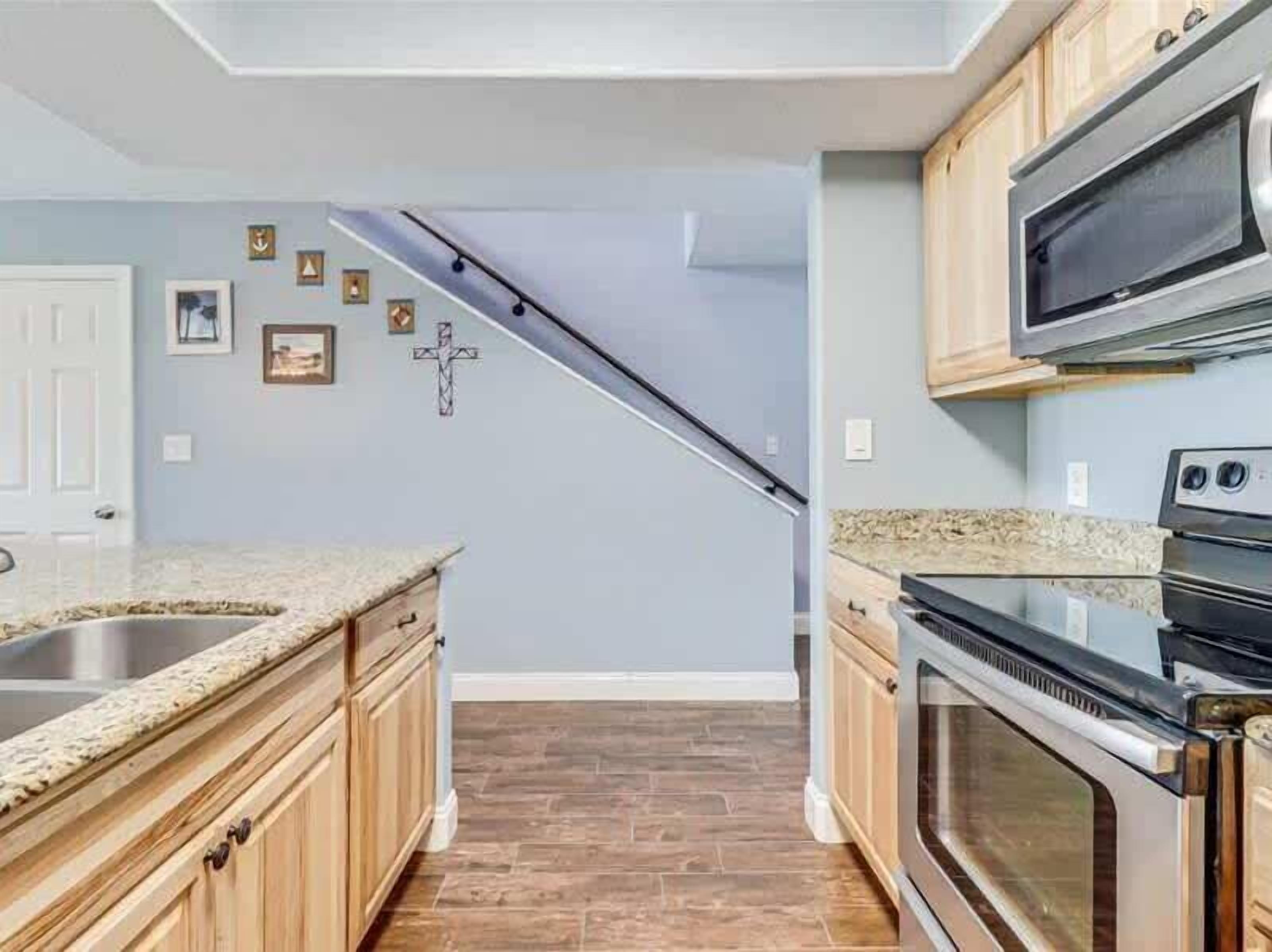 A kitchen with wooden cabinets, a granite countertop, a stainless steel oven, and a microwave.