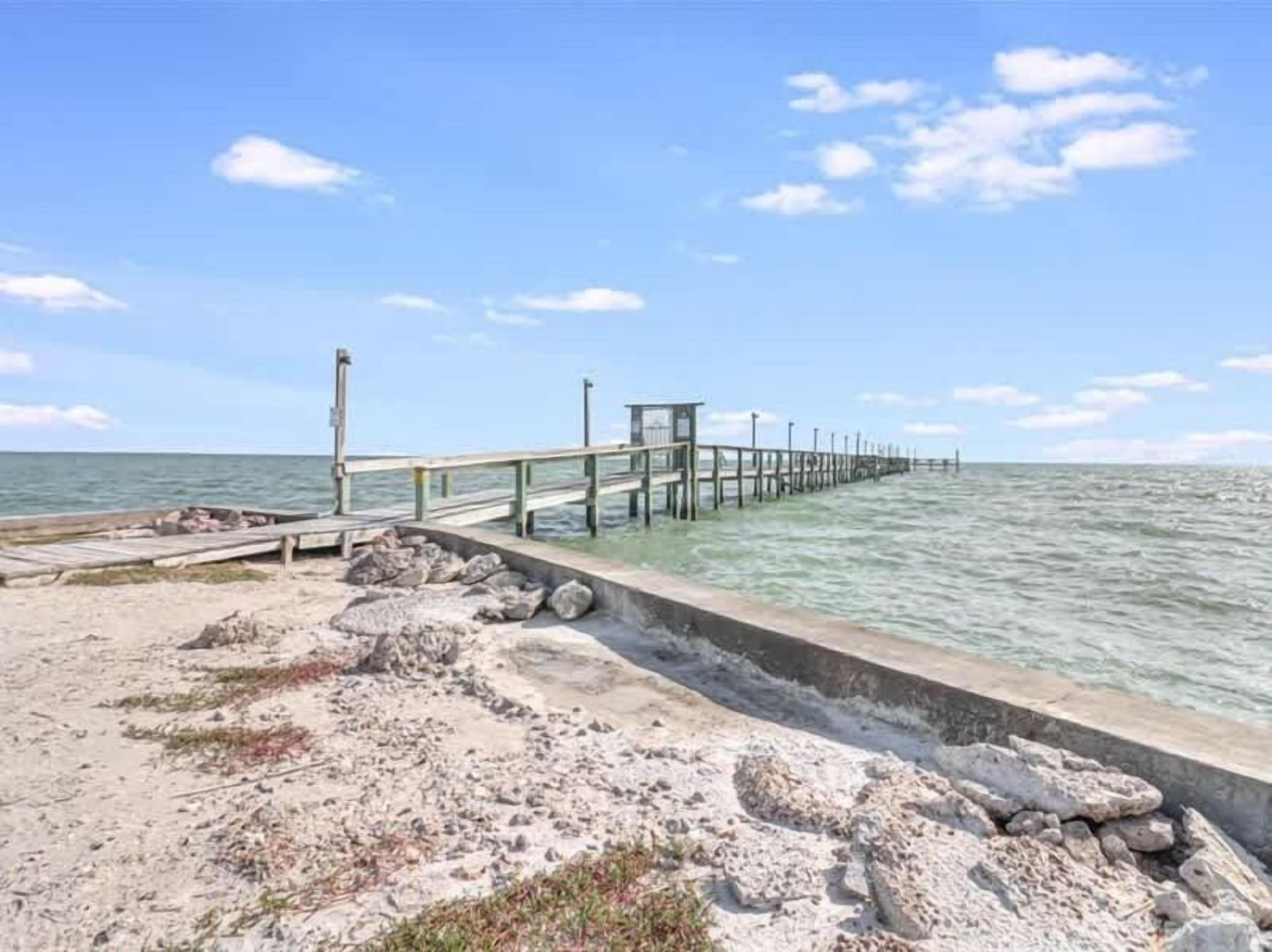 A pier extending into calm waters with a clear sky.