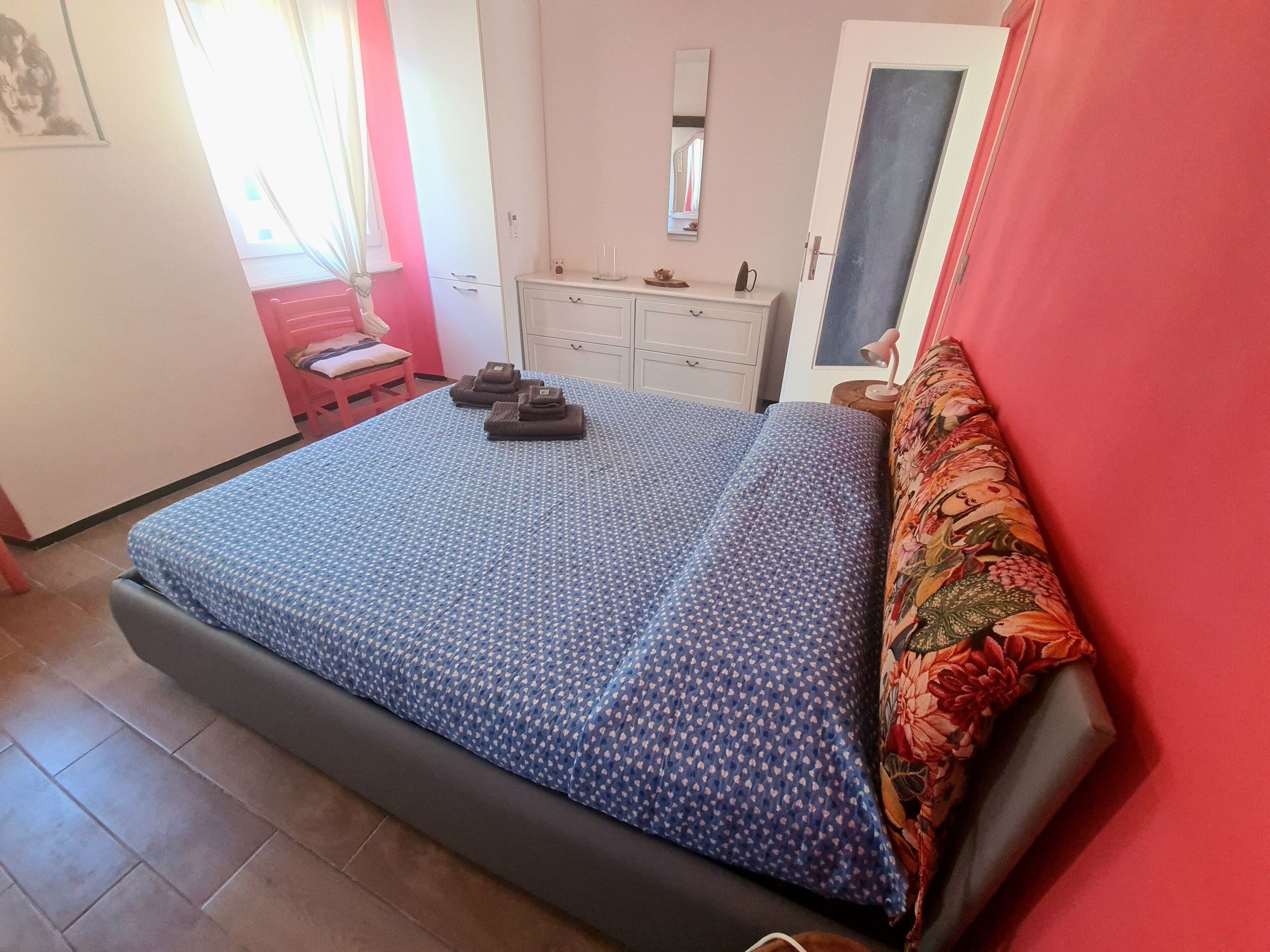 A bedroom with a bed, a dresser, a mirror, and a window with curtains.