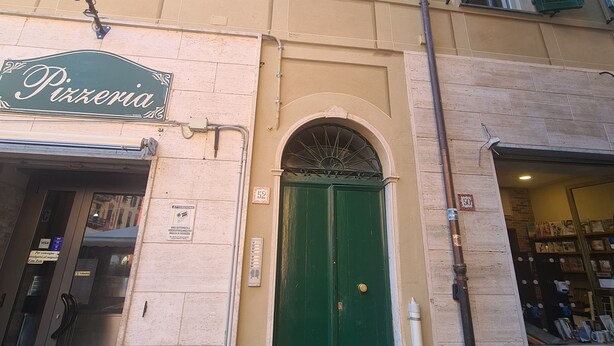 Ein Gebäude mit einer grünen Tür, einem Schild mit der Aufschrift 'Pizzeria' und der Nummer 52 über der Tür.