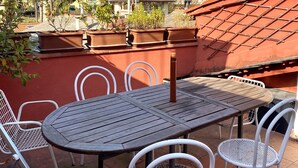 Eine Terrasse mit Tisch und Stühlen mit Blick auf einen Hang mit Gebäuden.