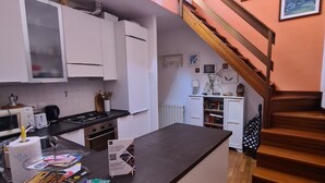 Eine Küche mit weißen Schränken, einer schwarzen Arbeitsplatte und einer Holztreppe.