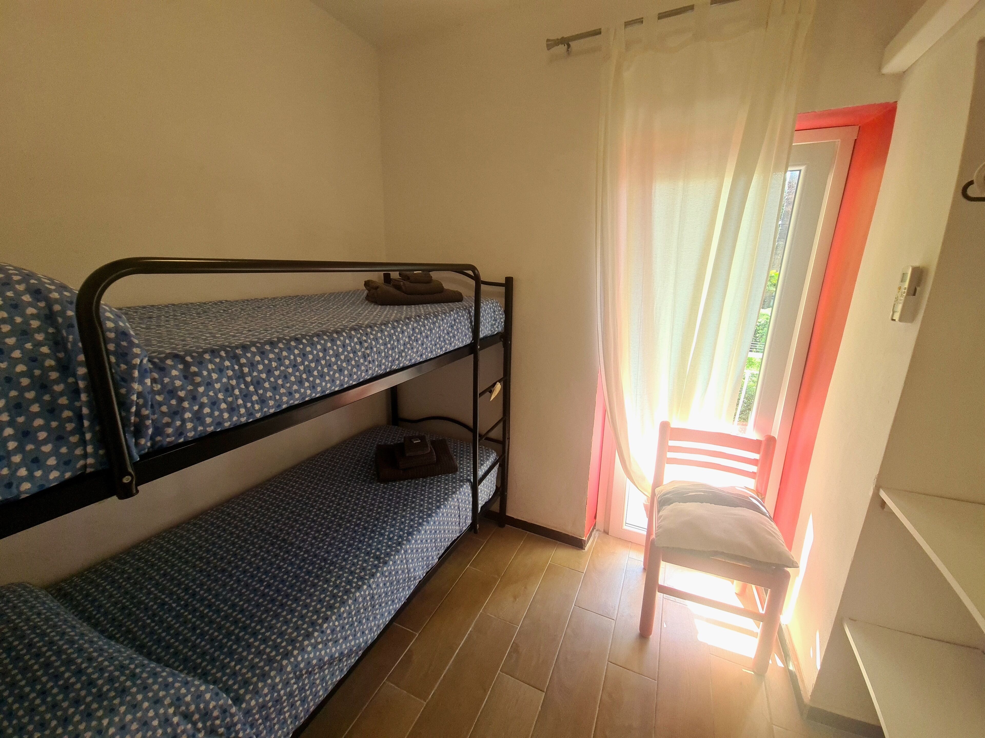 Ein Schlafzimmer mit Etagenbetten und einem Stuhl in der Nähe eines Fensters.