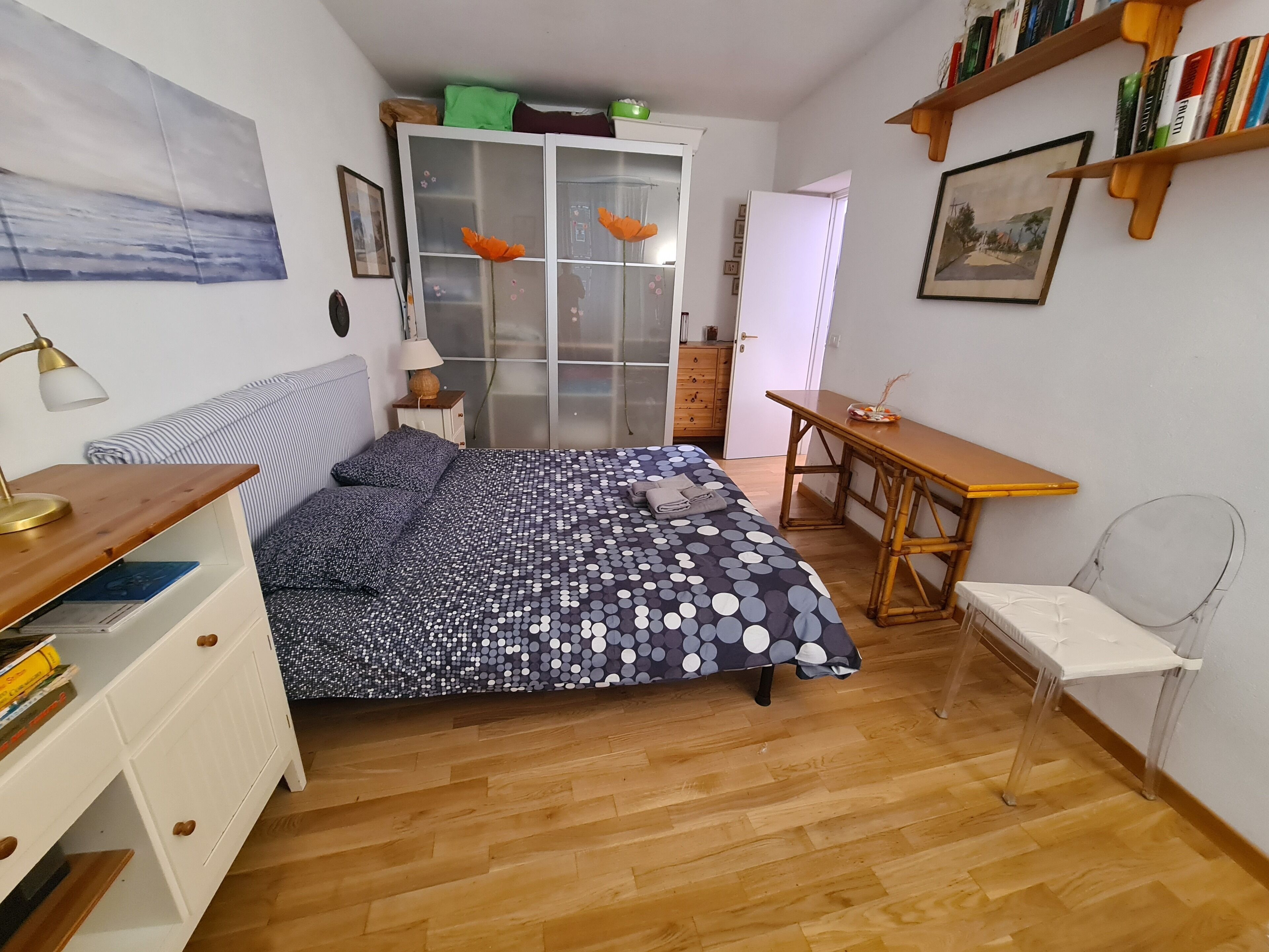 A bedroom with a bed, a desk, a chair, a wardrobe, and a bookshelf.