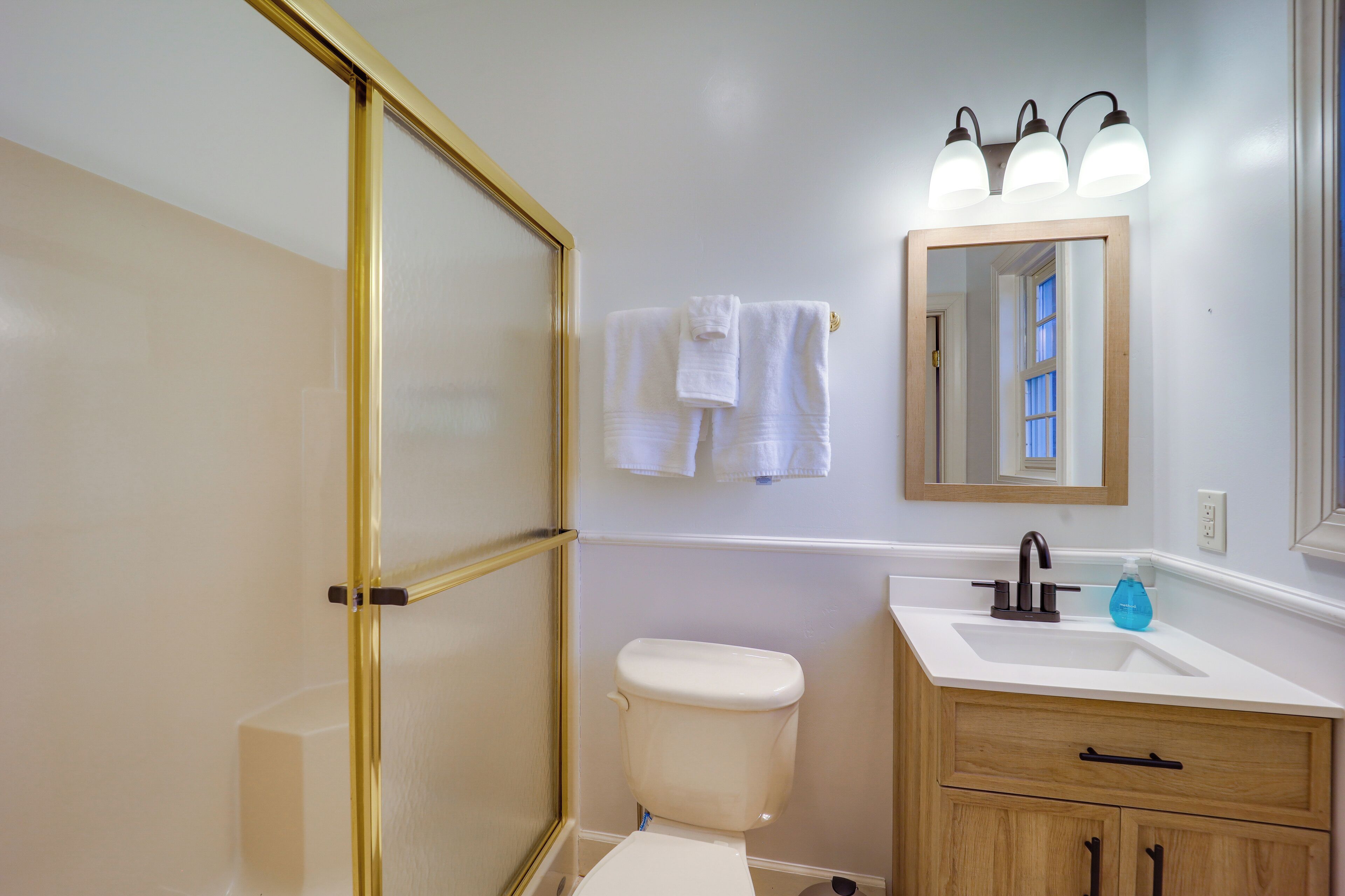A bathroom with a toilet, sink, and mirror.