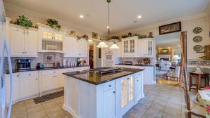 A spacious kitchen with white cabinetry, a large island, and a dining area with a table and chairs. - Immaculate Boone Villa w/ Entertainment Lounge! (Boone)