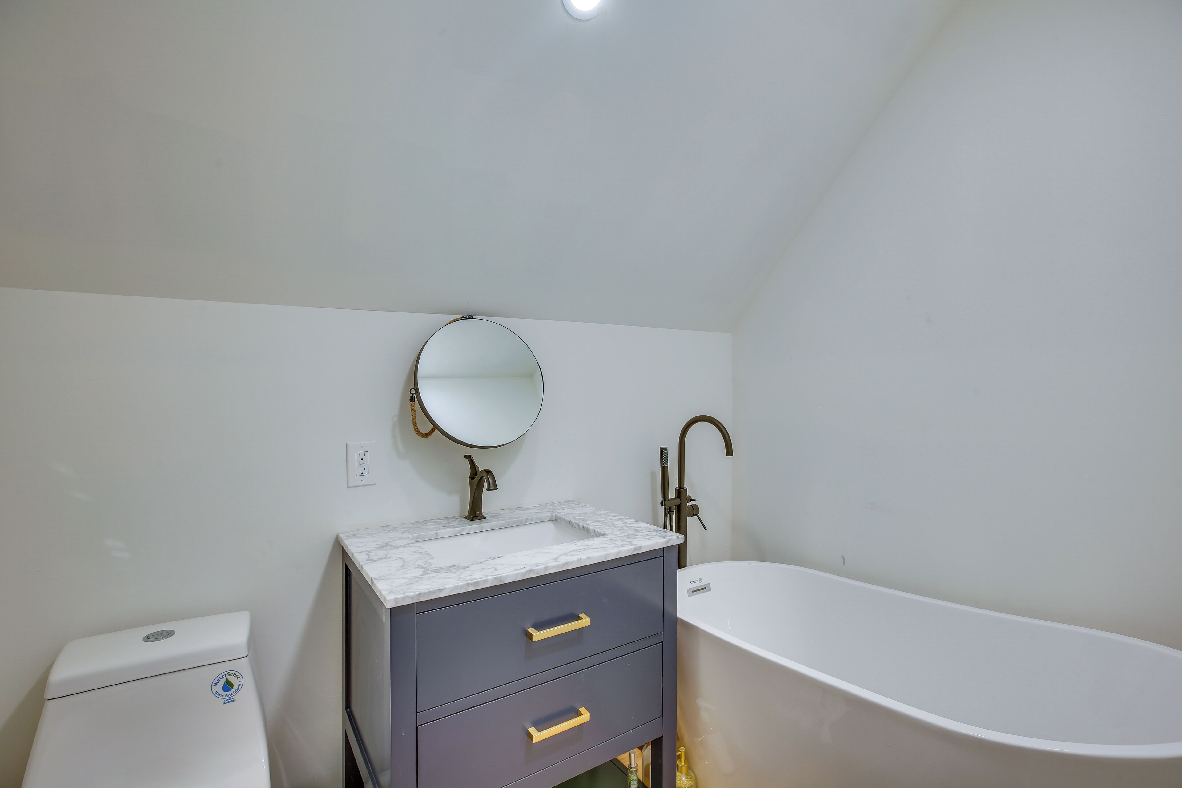 A bathroom with a white bathtub, a marble sink, and a toilet.