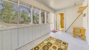 A spacious room with large windows, a wooden staircase, and a patterned rug. - Ruidoso Retreat w/ Grill ~ 3 Mi to Grindstone Lake (Ruidoso)