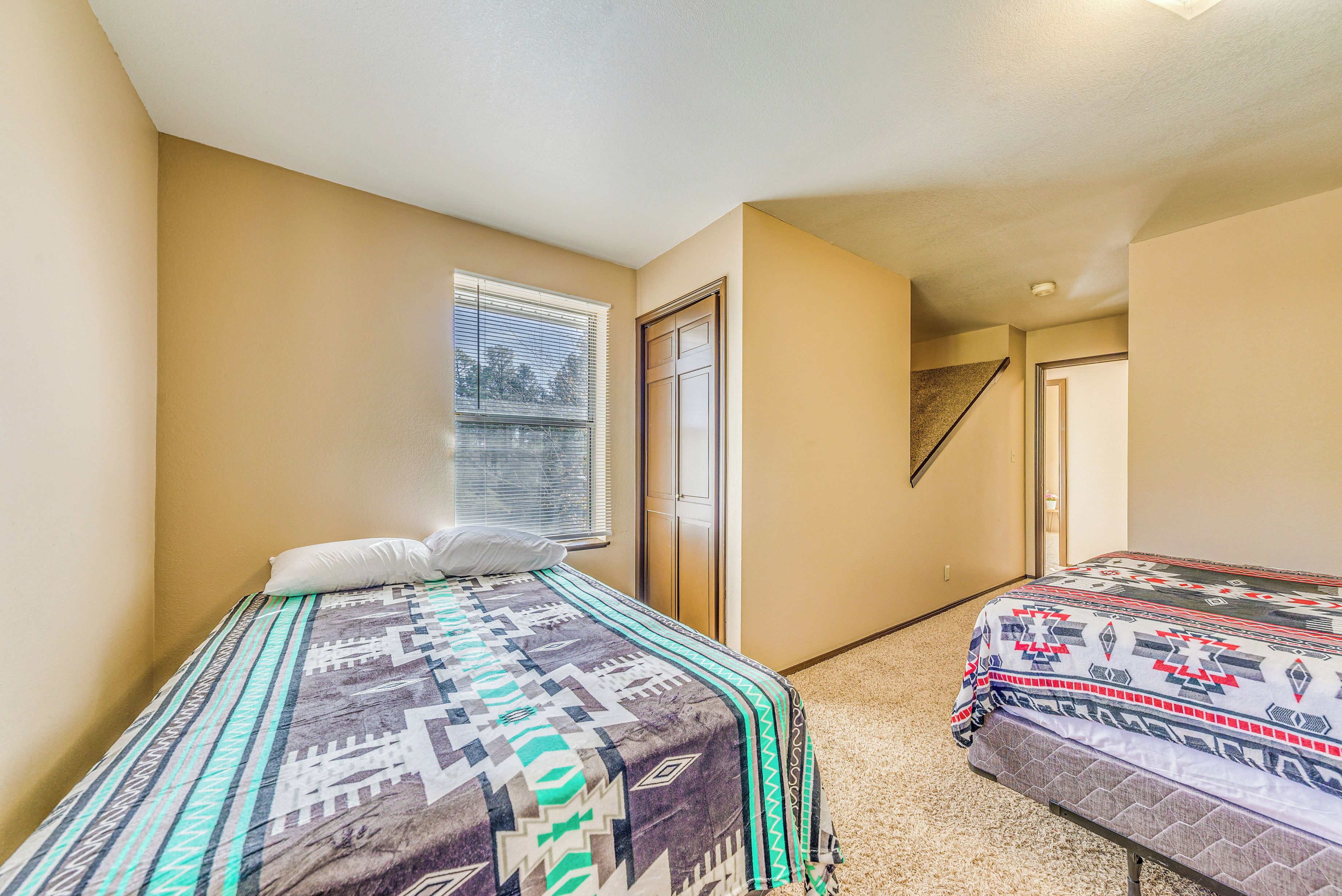 A bedroom with two beds, a window, and a door.