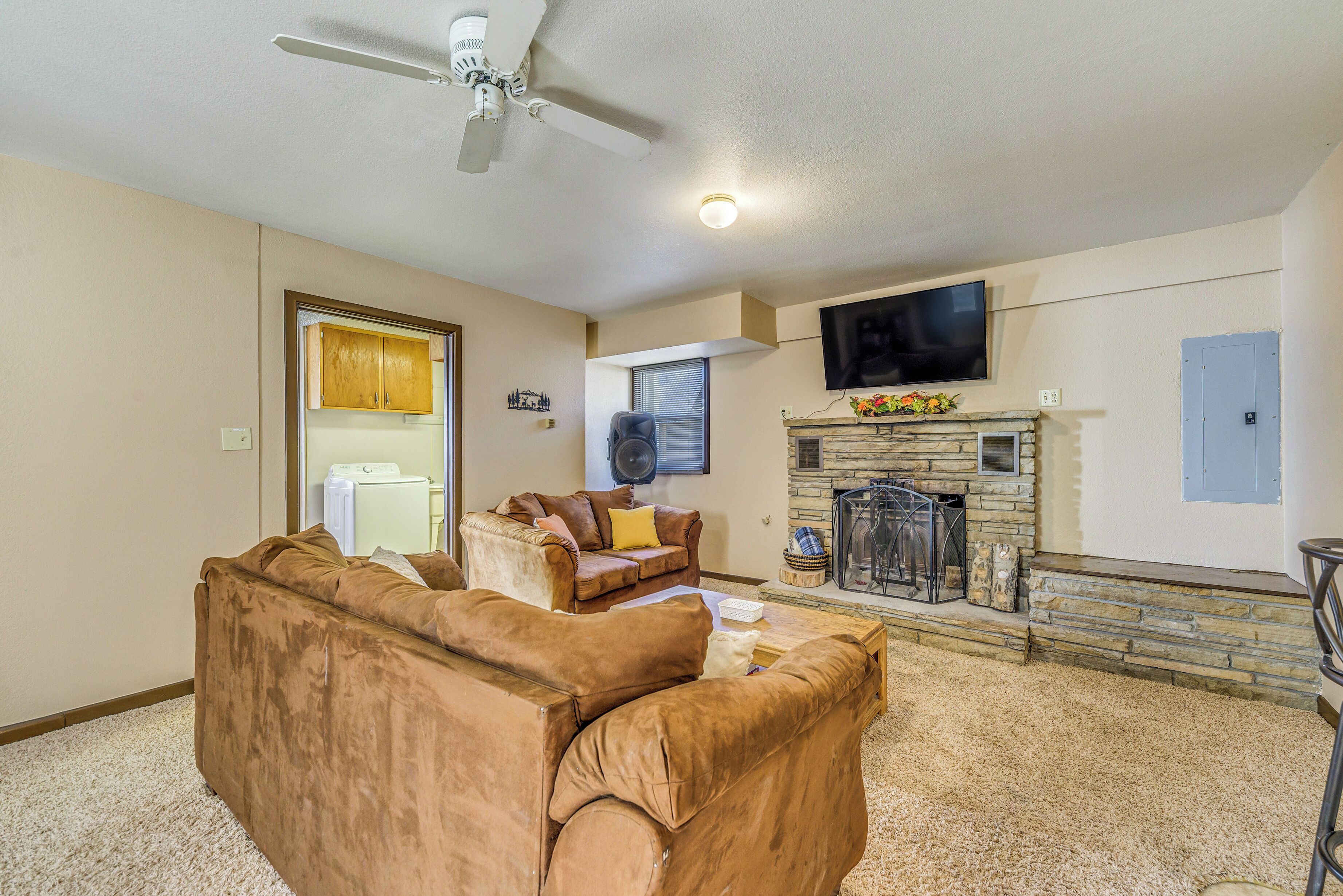 A living room with a fireplace, a television mounted above it, and a ceiling fan.