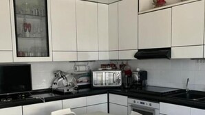 A modern kitchen with white cabinets, a black countertop, a toaster, a kettle, and a sink.
