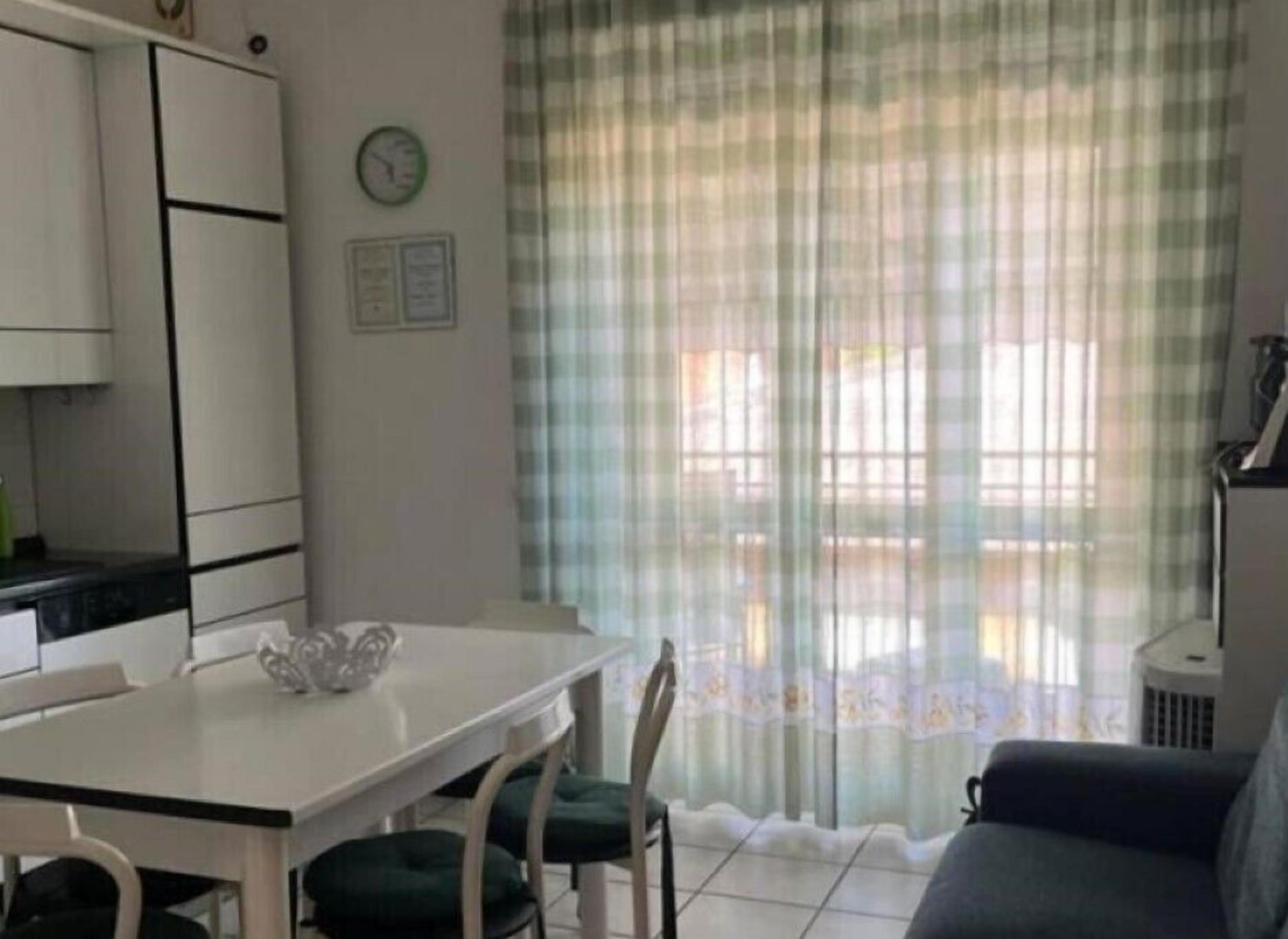 Eine kleine Küche mit Esstisch und Stühlen, einem Sofa und einem Fenster mit Vorhängen.
