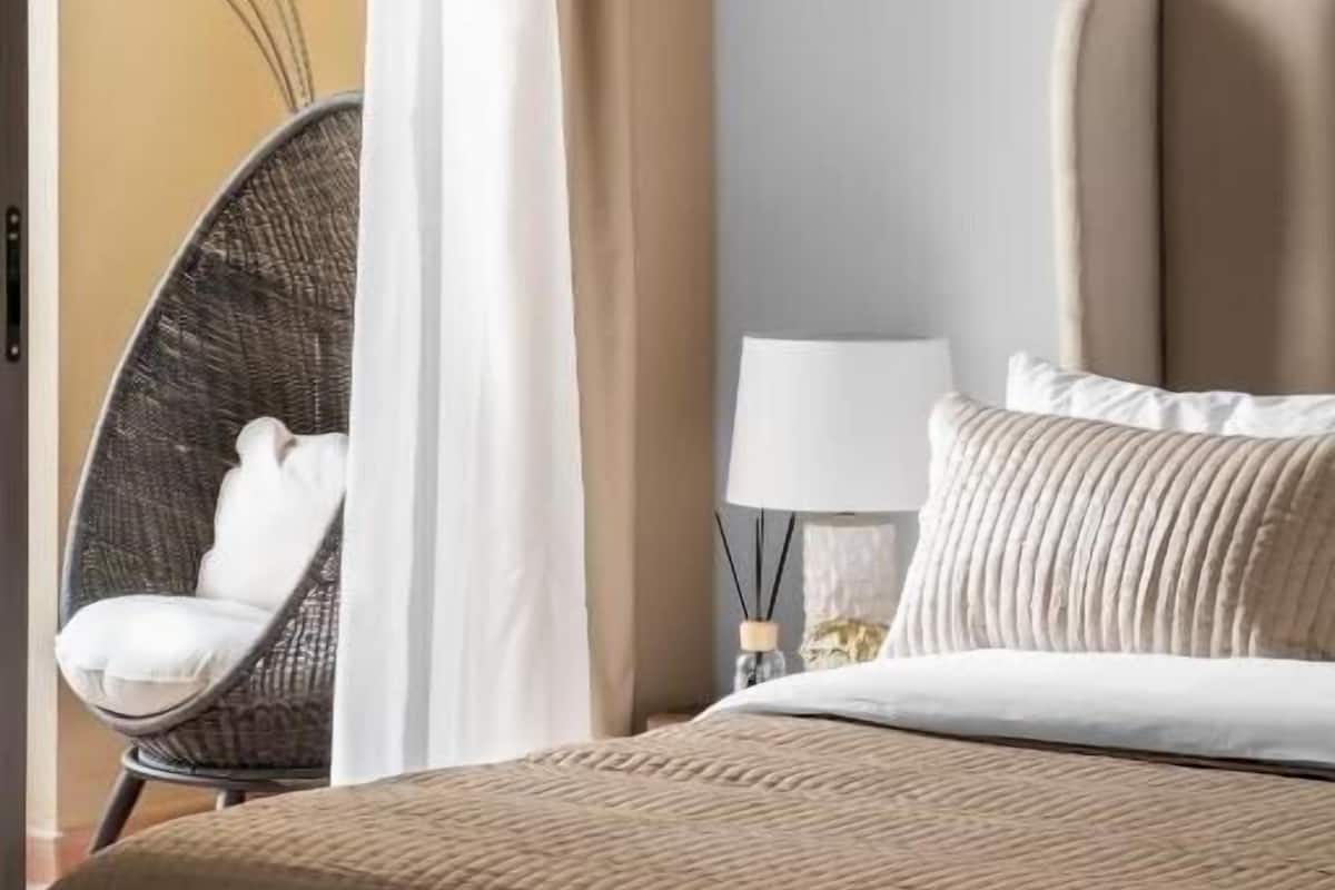 A bedroom with a bed, a chair, a lamp, and a curtain.