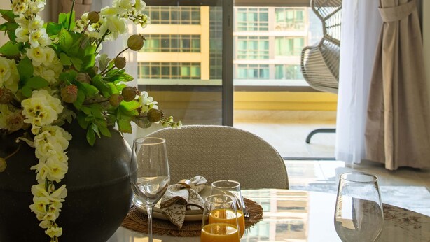 A dining table set with plates, cutlery, and a vase of flowers.