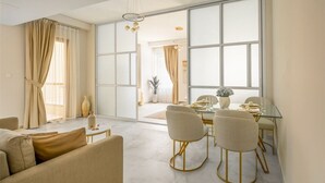 A modern living room with a sofa, a coffee table, and a dining area with a glass table and chairs.