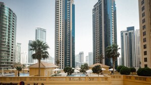A high-rise residential building complex with multiple balconies and a central courtyard with palm trees and outdoor seating.