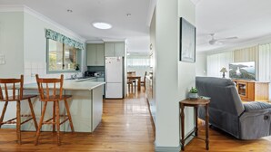 Una cocina amplia con piso de madera, un comedor con mesa y sillas, y un sofá gris en una sala de estar.