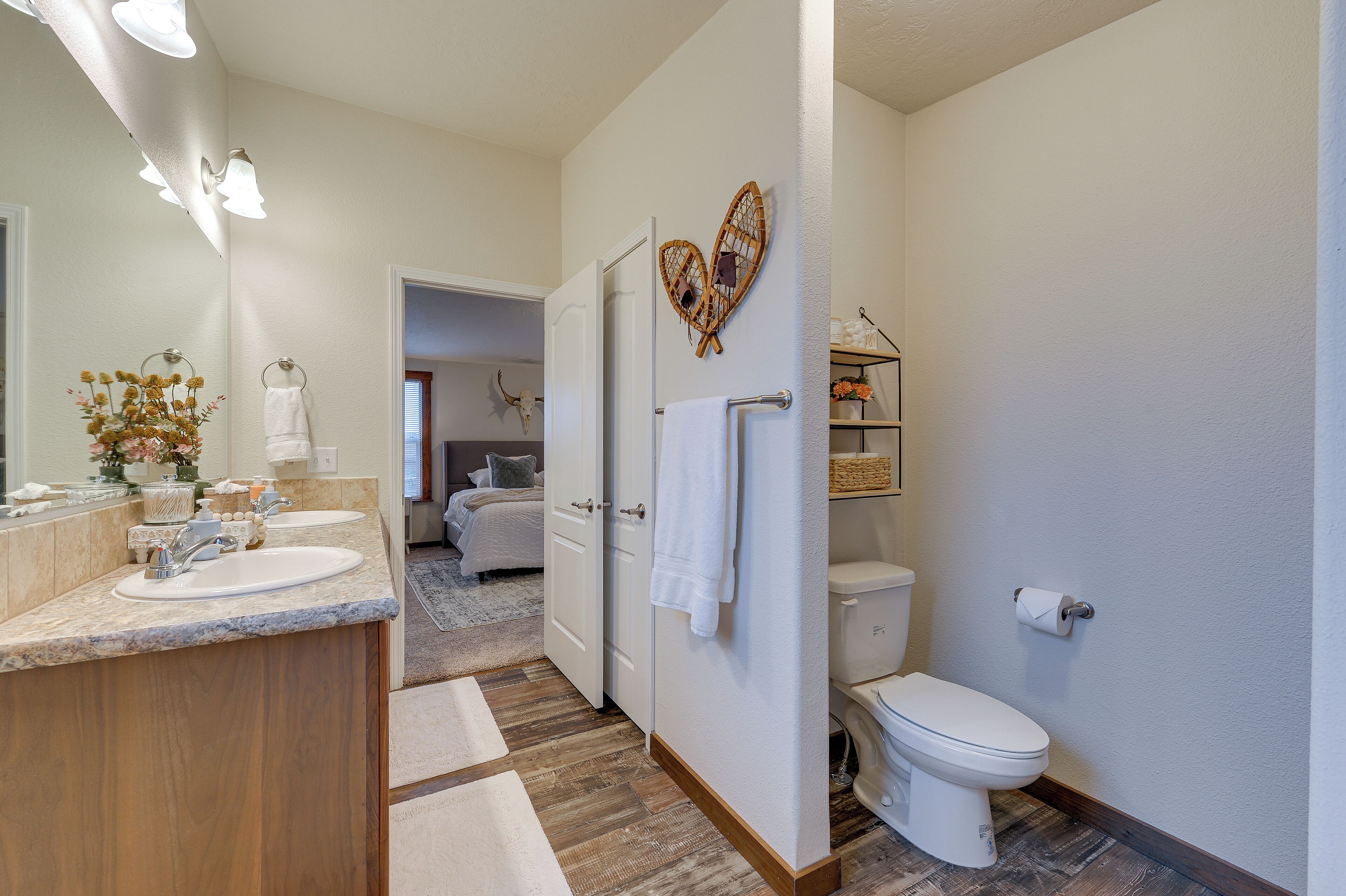 Un baño moderno con tocador de madera, dos lavamanos, un inodoro y zona de ducha.