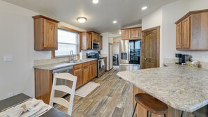 A kitchen with wooden cabinets, granite countertops, stainless steel appliances, and a bar area. - Beautiful Tetonia Escape w/ Porch & Teton Views (Tetonia)