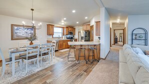 A spacious kitchen with wooden cabinets, a central island with stools, and a dining area with a white table and chairs. - Beautiful Tetonia Escape w/ Porch & Teton Views (Tetonia)