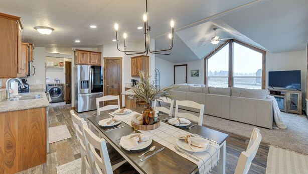 A modern kitchen with wooden cabinets, a dining area with a long table set for four, and a large window overlooking a scenic view. - Beautiful Tetonia Escape w/ Porch & Teton Views (Tetonia)