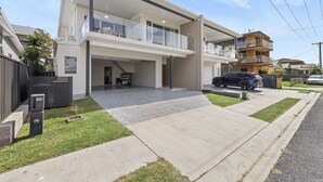 Une maison moderne à deux étages, dotée d’un garage, d’une allée couverte et d’un petit jardin à l’avant.