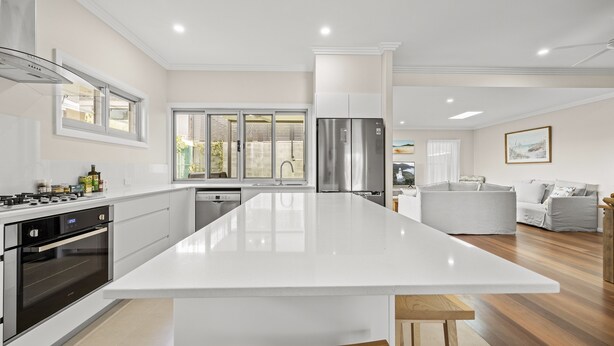 Une cuisine moderne dotée d’un grand îlot central, d’appareils électroménagers en acier inoxydable et donnant sur le jardin.