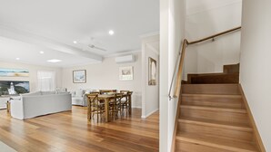 Un vaste espace de vie comprenant un escalier en bois, une table à manger et un canapé.