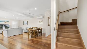 A spacious living area with a wooden staircase, a dining table, and a sofa.