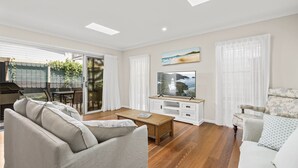 Un salon avec un canapé, une table basse, un téléviseur et un fauteuil.