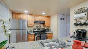 Eine moderne Küche mit Granit Arbeitsplatten, Edelstahlgeräten, Holzschränken und einem eingebauten Backofen.