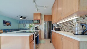 A modern kitchen with wooden cabinets, stainless steel appliances, and a tiled backsplash. - Oceanfront Kihei Condo With On-site Beach Access! (Kihei)