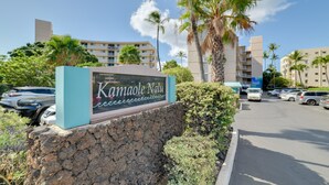 A sign for Kamaole Nalu with a parking lot and palm trees in the background. - Oceanfront Kihei Condo With On-site Beach Access! (Kihei)