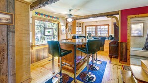Un intérieur en bois avec un espace bar, un plancher en bois et un mur d’accent de couleur rouge.
