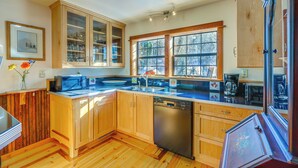 Une cuisine moderne avec des meubles en bois, un lave-vaisselle et une grande fenêtre qui laisse entrer la lumière naturelle.