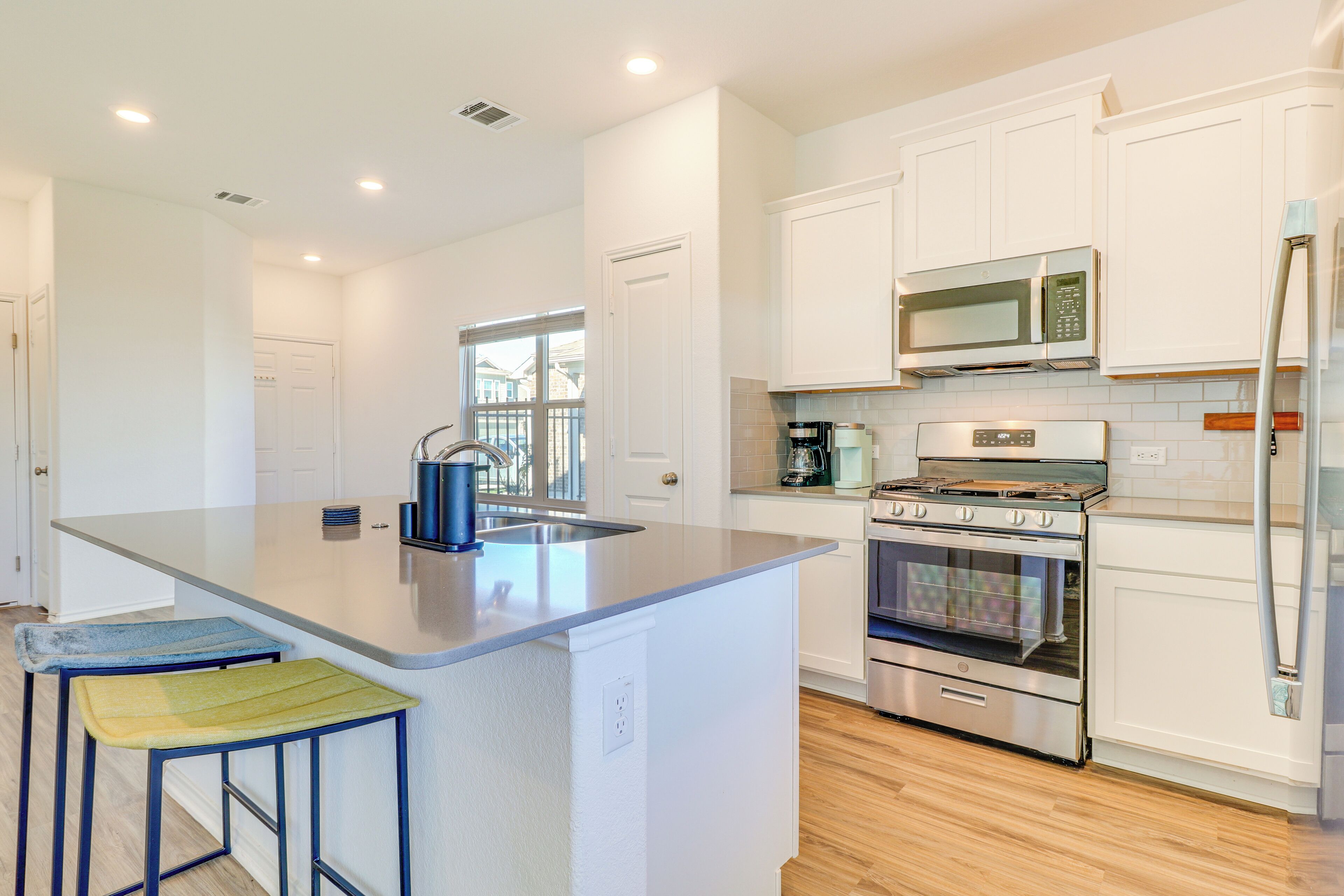 A modern kitchen with white cabinets, stainless steel appliances, and a central island with stools.